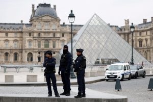 Police officers stand near the pyramid of the Louvre museum after reports of a robbery, in Paris, France, October 19, 2025. REUTERS/Gonzalo Fuentes